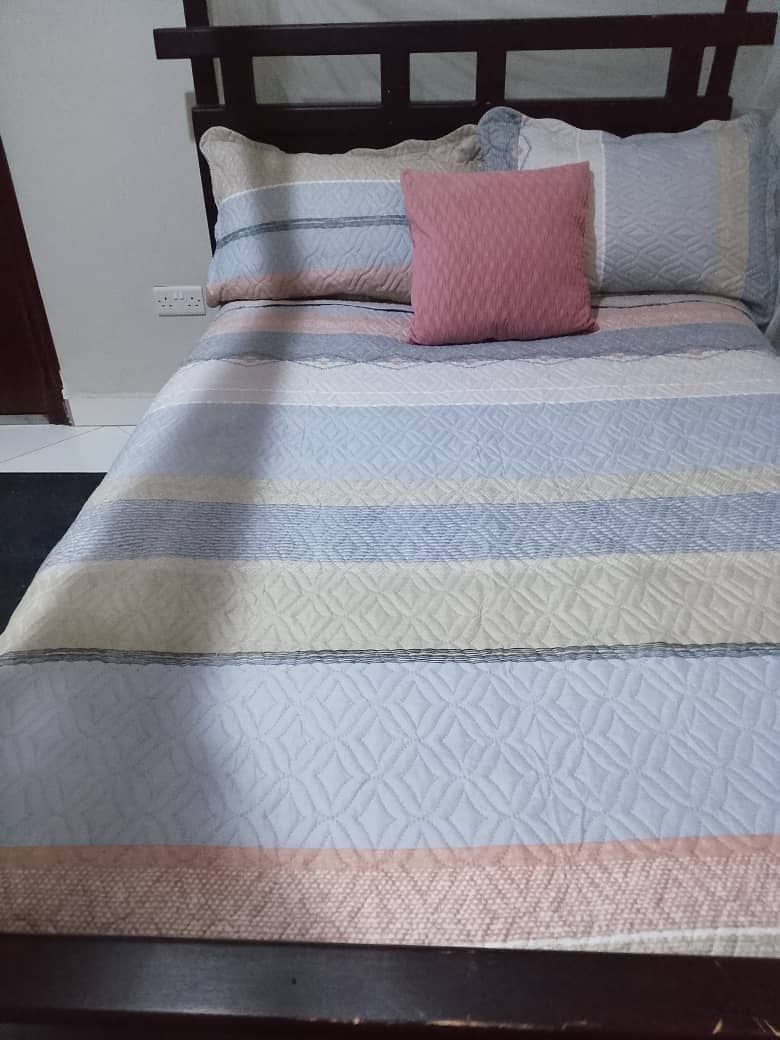 A bed with a patterned bedspread and multiple pillows.