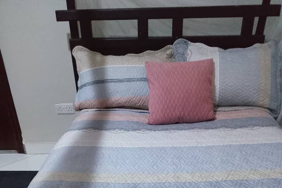 A bed with a patterned bedspread and multiple pillows.
