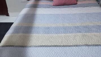 A bed with a patterned bedspread and multiple pillows.