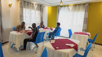 A dining area with round tables, chairs, and a yellow wall.