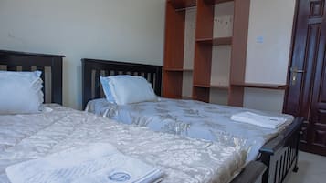 A bedroom with two beds, a wardrobe, and a door.