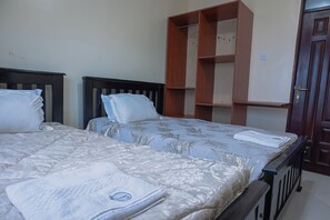 A bedroom with two beds, a wardrobe, and a door.