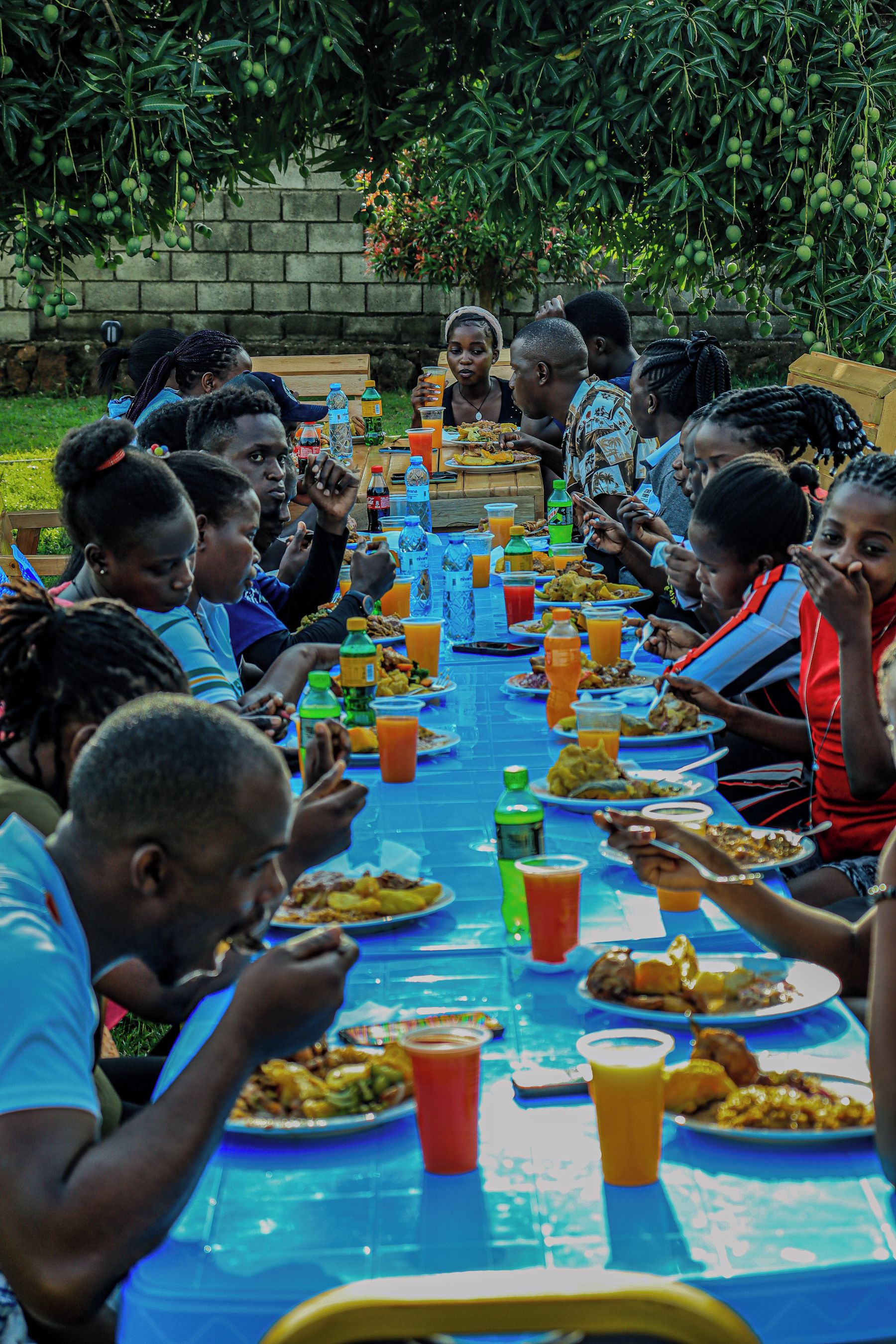 A group of people seated around a long table with various food items and drinks.