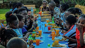 A group of people seated around a long table with various food items and drinks.