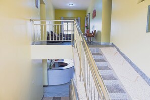 A multi-level interior with a staircase, a reception desk, and seating area. - MSGR NGOBYALAKEVIEW HOTEL (Entebbe)