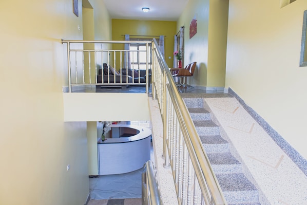 A multi-level interior with a staircase, a reception desk, and seating area.