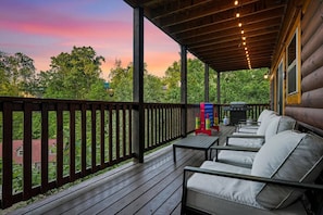 A wooden deck with outdoor seating and a barbecue grill. - Sleeps 12, Private Indoor Pool, Hot Tub, Theater, Arcade, 6 Mi to Dollywood (Pigeon Forge)