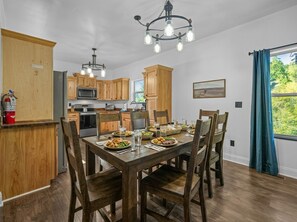 Una cocina moderna con armarios de madera, una mesa de comedor lista para cuatro personas y una lámpara de araña.
