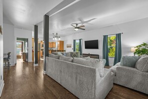 A spacious living room with a large sectional sofa, a flat-screen TV, and a ceiling fan. - Sleeps 10, King Bed in Every Room, Hot Tub, Views, 3 Mi to Downtown Gatlinburg (Gatlinburg)