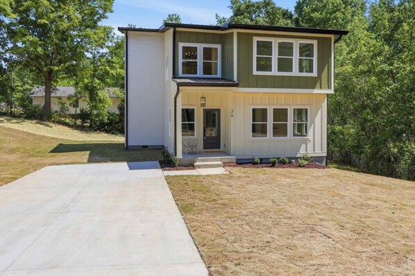 A two-story house with a front porch, a garage, and a well-maintained lawn.
