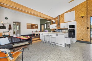 A modern kitchen with white cabinets, a wooden accent wall, and a built-in oven. - Heritage Haven - A Sepal Stay (Perth)