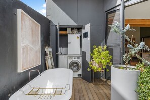 A compact outdoor laundry area with a washing machine, a drying rack, and a small potted plant. - Heritage Haven - A Sepal Stay (Perth)
