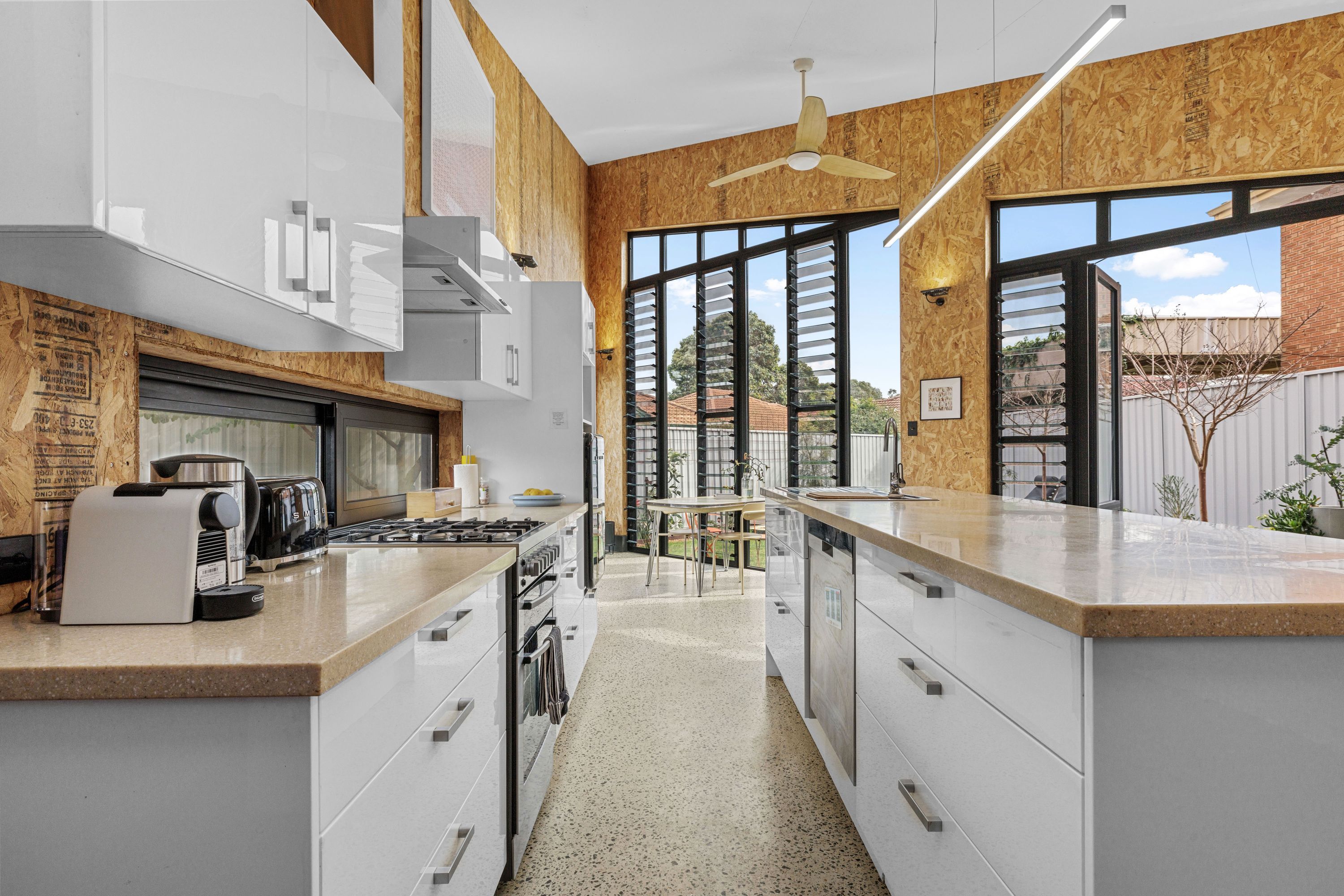 Una cocina moderna con gabinetes blancos, una estufa de acero inoxidable y un amplio ventanal.