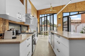 A modern kitchen with white cabinets, a stainless steel range, and a large window.