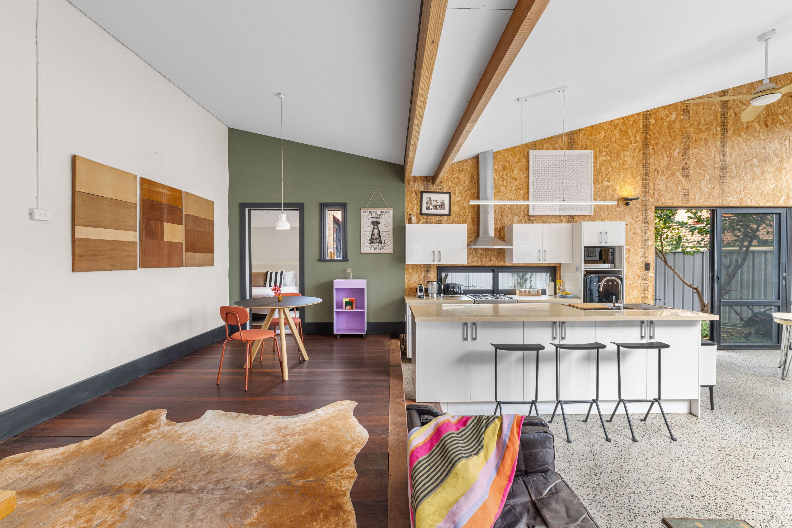 Una cocina moderna con una isla central, taburetes de bar y una zona de comedor con mesa y sillas.