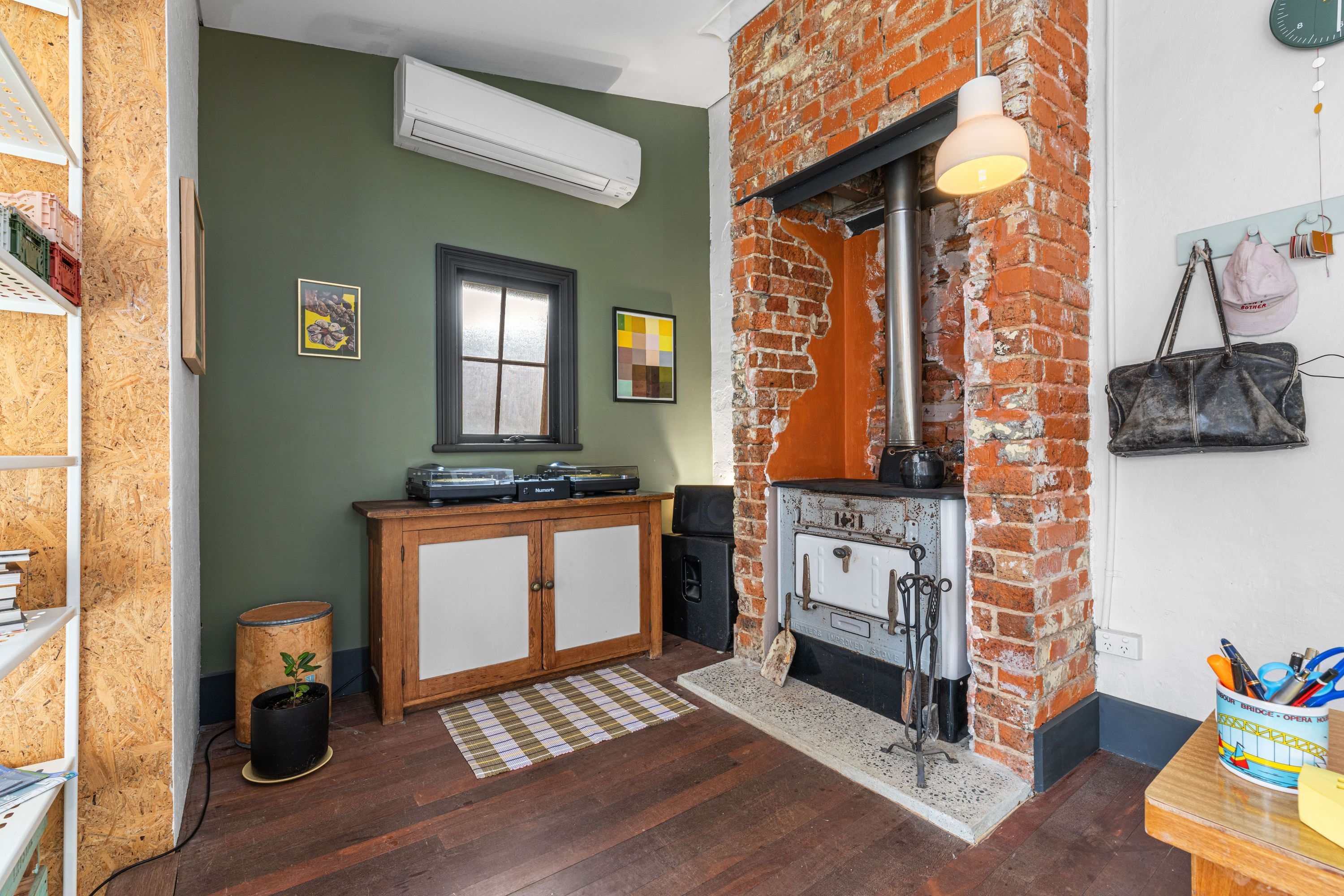 A kitchen with a brick wall, a wooden cabinet, a stove, and a hanging light fixture.