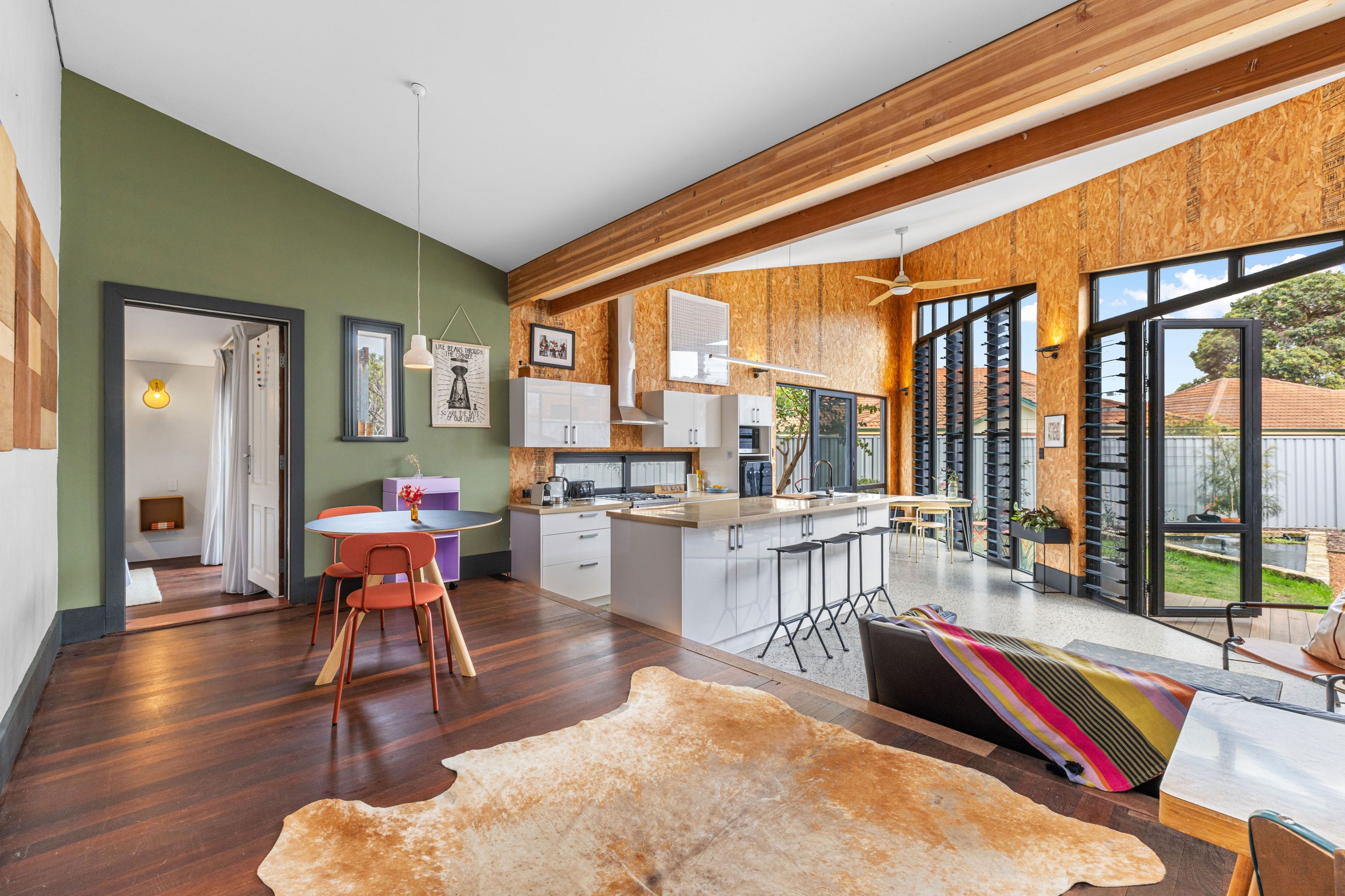 Una cocina moderna con una isla central, vigas de madera y ventanas amplias.