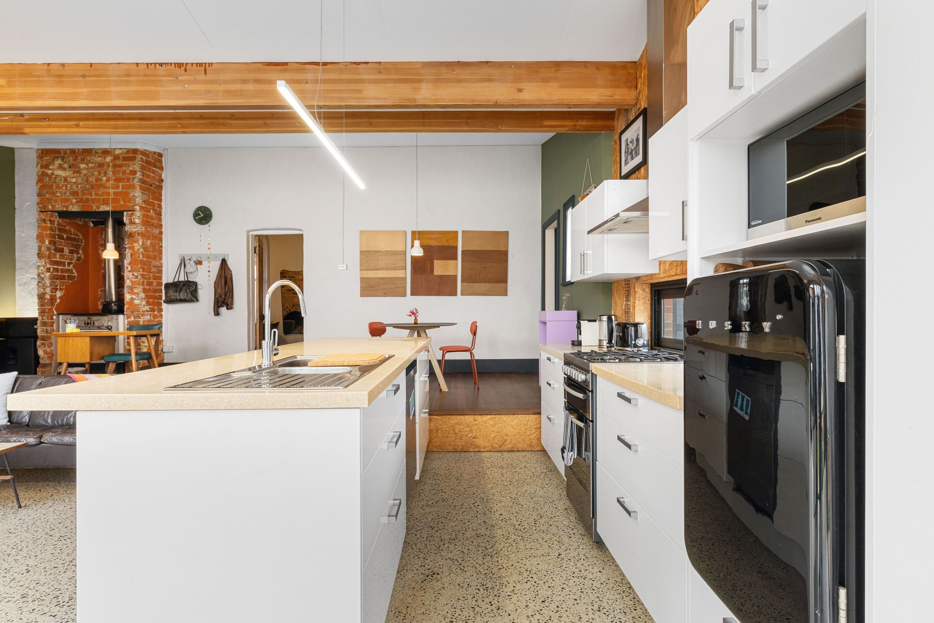 A modern kitchen with white cabinetry, a central island, a stove, and a refrigerator.