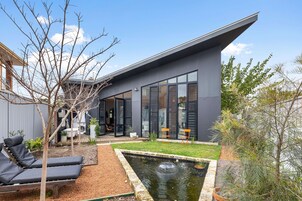 Uma casa moderna com uma grande porta de vidro, um pequeno jardim e uma piscina.