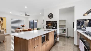 Una cocina moderna con una isla central, un comedor con mesa y sillas, y una sala de estar con sofá.