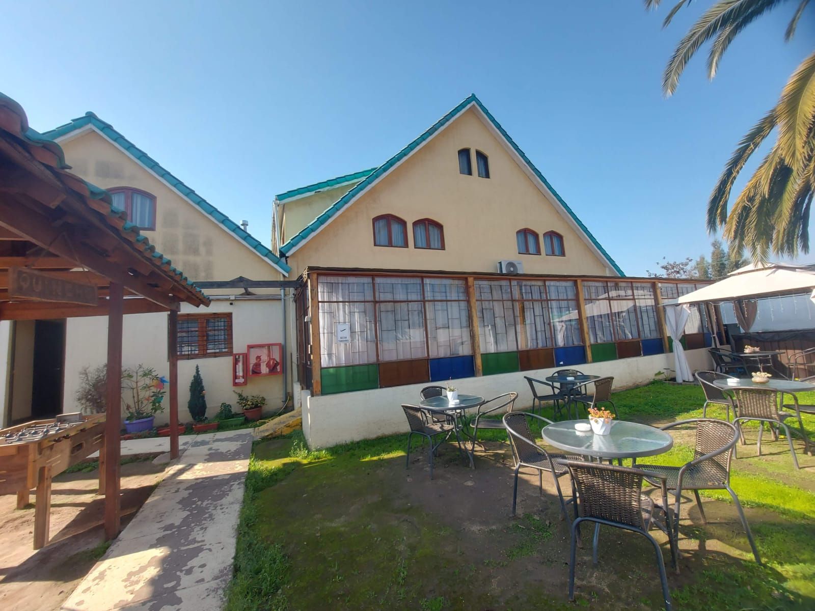 Un bâtiment doté d’un toit à deux versants, de grandes fenêtres et d’un patio couvert avec des sièges d’extérieur.