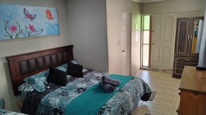 Un dormitorio con cama, un cuadro, una puerta y vista a otra habitación con armario.