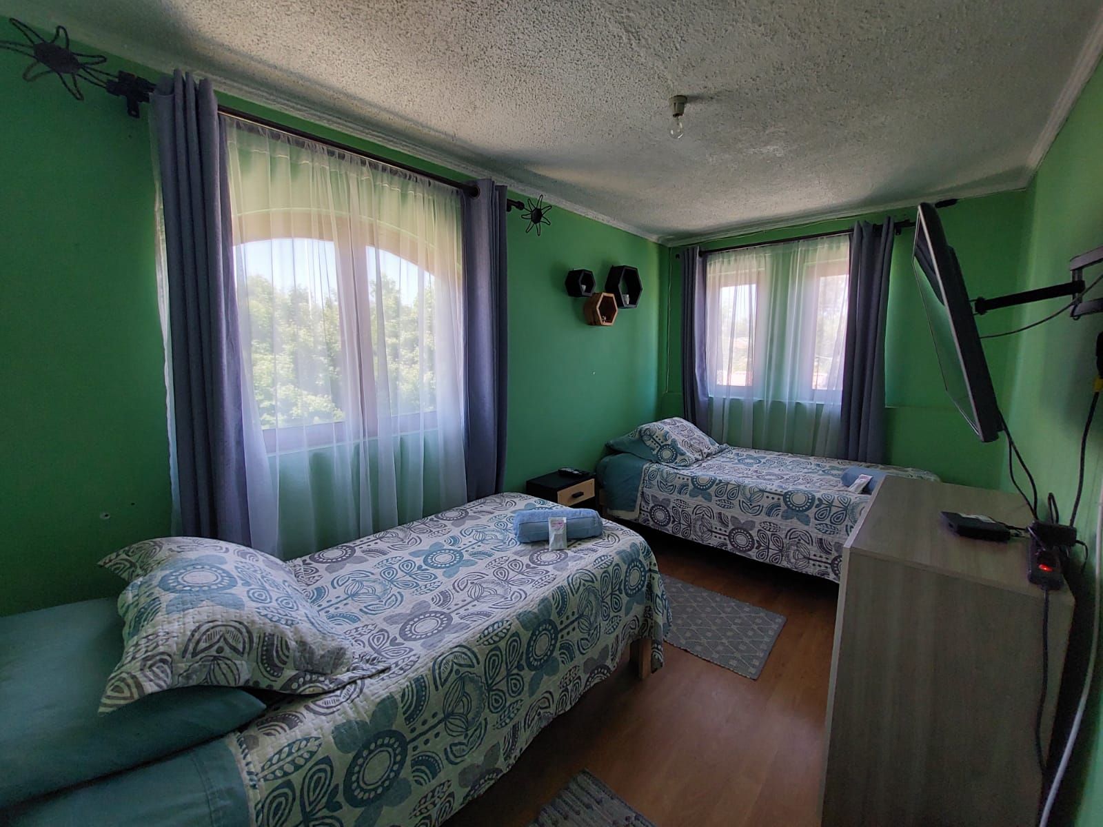 A room with two beds, a desk, and a ceiling fan.