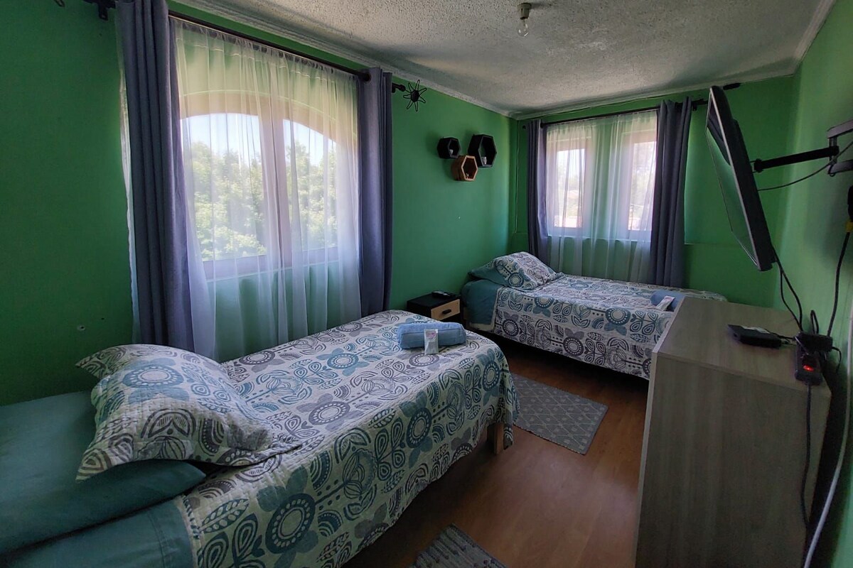 Una habitación con dos camas, un escritorio y un ventilador de techo.