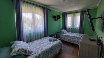 A room with two beds, a desk, and a ceiling fan.
