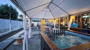 Un espace extérieur aménagé avec des tables et des chaises, protégé par un grand parasol, et offrant une vue sur une piscine.