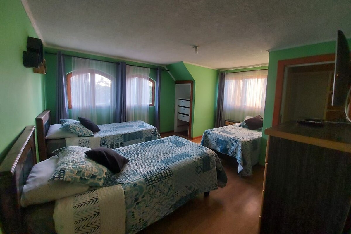 Una habitación con dos camas, un aparador y un televisor.