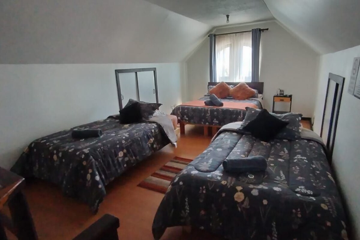 Una habitación con dos camas, un escritorio y una ventana.