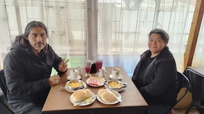 Two people seated at a table with breakfast items including eggs, bread, and beverages.