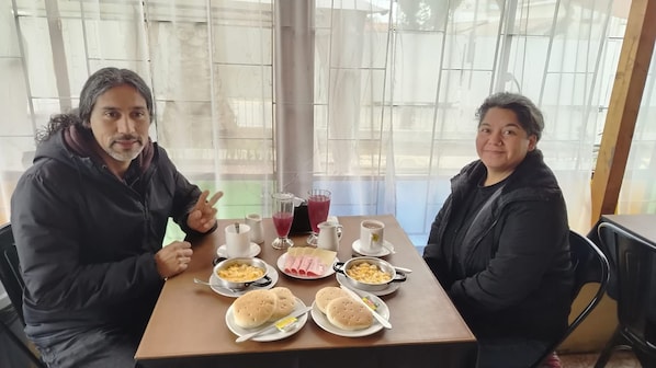 Two people seated at a table with breakfast items including eggs, bread, and beverages.