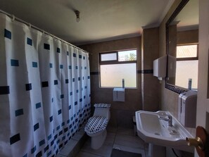 Un baño con inodoro, lavamanos y cortina de ducha.