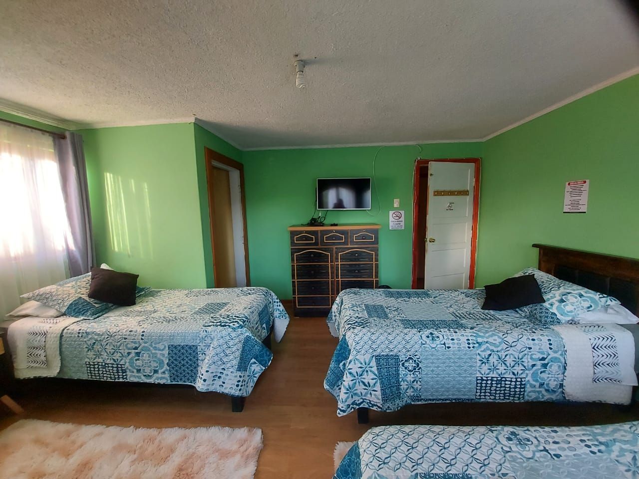 A room with two beds, a television on the wall, and a dresser.
