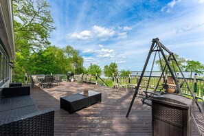 A deck with outdoor furniture, a swing set, and a view of a body of water. - The April Inn - A Historic Victorian Lakehouse (Spring Grove)