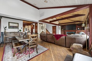 A spacious living area with a wooden dining table, a sofa, and a fireplace. - The April Inn - A Historic Victorian Lakehouse (Spring Grove)