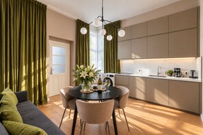 A modern kitchen with a dining area, featuring a round table with chairs, a coffee machine, and a vase with flowers. - Elegant Prague Apt•Wenceslas Square• City Center (Praha)