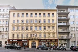 A multi-story building with a central entrance, a sign for 'BLACK PANTHER' on the ground floor, and several parked cars and motorcycles in front. - Elegant Prague Apt•Wenceslas Square• City Center (Praha)