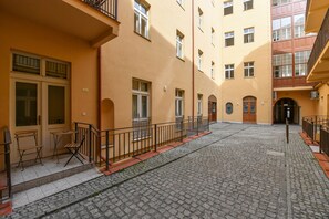 A courtyard with cobblestone pavement, a wooden bench, and a metal railing. - Elegant Prague Apt•Wenceslas Square• City Center (Praha)
