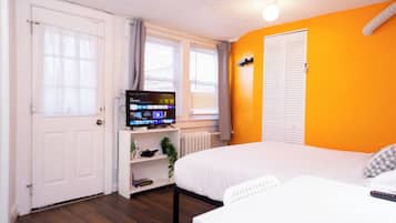 Une chambre à coucher avec un lit, une télévision, une étagère avec des objets et une fenêtre.