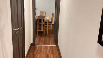 Un pasillo con piso de madera que conduce a un comedor con mesa y sillas.