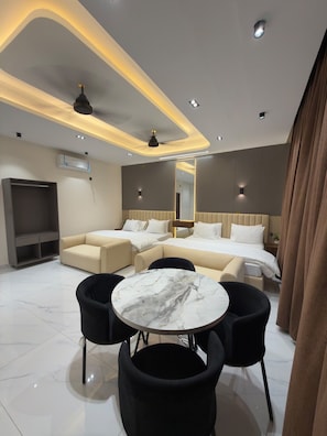 Quarto de hotel moderno com sofá, cama, mesa de jantar e espelho.
