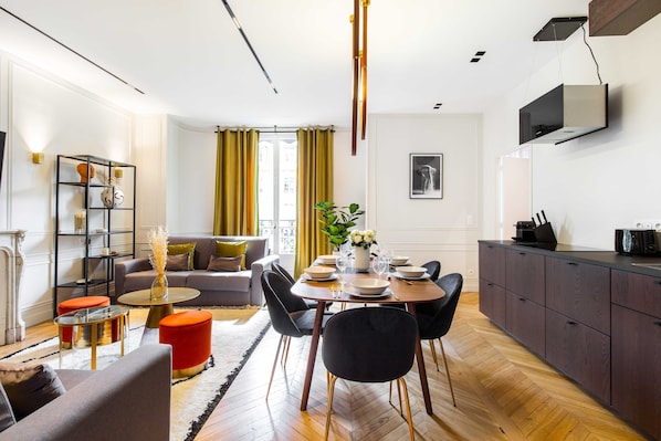 Ein modernes Wohnzimmer mit Essbereich, einer Küche und Blick auf die Stadt.