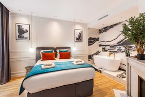 Ein modernes Hotelzimmer mit einem großen Bett, einer Badewanne und Marmorwandverkleidung.