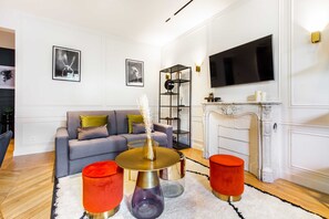 Ein Wohnzimmer mit grauem Sofa, einem runden Couchtisch und einem Kamin.