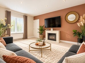 A living room with a fireplace, a flat-screen TV, and a round coffee table. - Beautiful 5-Bedroom House • Detached • Driveway Parking • Super-Fast Wifi • SmartTVs • Yoko Property (Milton Keynes)