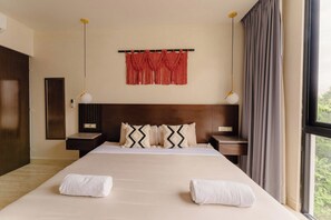 A hotel room with a large bed, two bedside tables, a headboard, a wall-mounted macrame piece, and a window with curtains. - Elegant 3BR Penthouse with Private Rooftop Pool (Tulum)