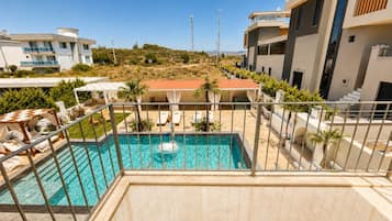 Un immeuble résidentiel moderne doté d’une piscine, d’un espace extérieur aménagé et offrant une vue sur le paysage environnant.